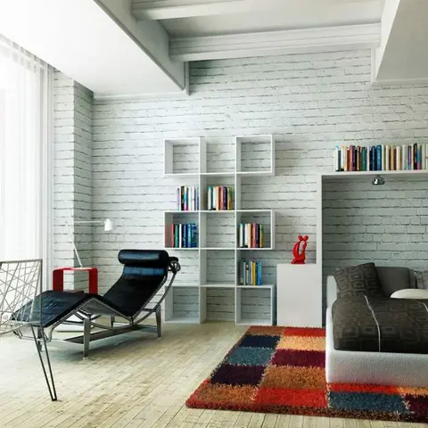 Whitewashed brick loft under exposed beams with the bed in a recessed alcove under a book ledge