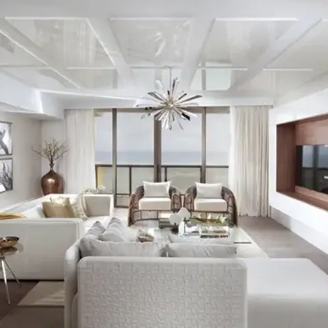 Wide all-white living room with a sputnik chandelier over two swivel armchairs, a walnut-lined recess in the gloss white TV wall and a fan-shaped wood wall