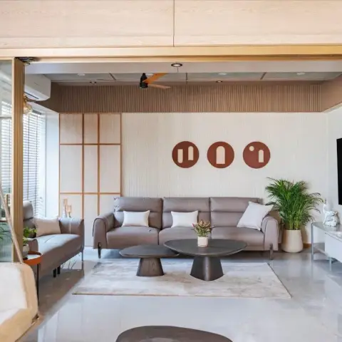 Wide living room with a taupe leather recliner sofa under three round terracotta wall discs, twin dark mushroom coffee tables on a beige rug