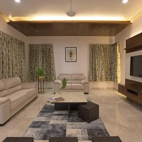 Wide living room with two cream leather sofas facing a white stone TV wall banded in walnut, a slatted wood ceiling raft with cove lighting overhead