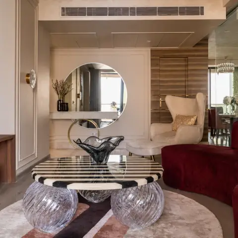 Wine-red curved velvet sofa facing a striped-stone round coffee table carried on three cut-glass sphere legs