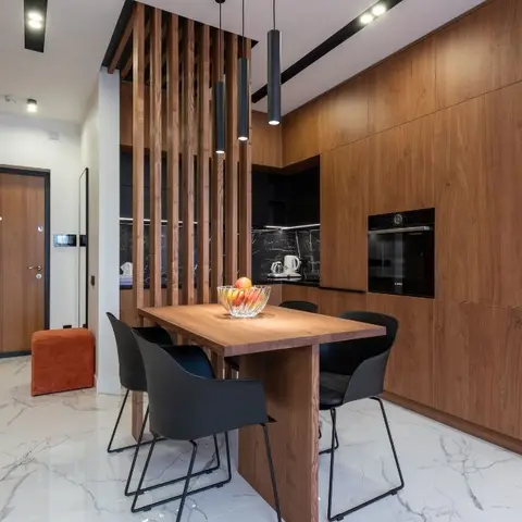 Wood-panelled dining nook with black cylindrical pendant lights over a wooden table