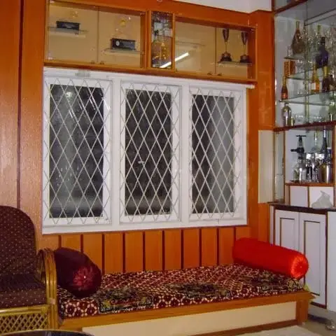 Wood-panelled living room nook with a built-in glass-front bar display case, lattice-grille windows and a cushioned window-seat bench.