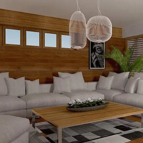 Wood-panelled living room with a grey L-shaped sectional, two woven rattan globe pendants and a wood coffee table on a geometric grey rug.