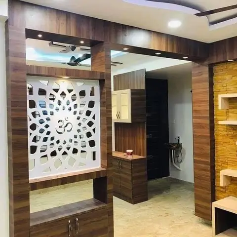 Wood-panelled pooja alcove with a white CNC-cut Om jaali screen and a cabinet base unit below