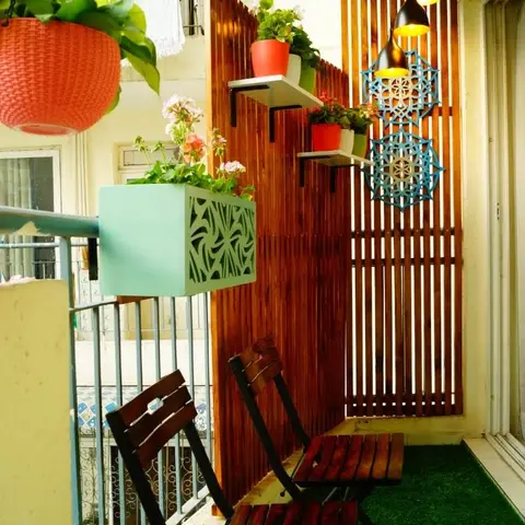 Wood-slat privacy screen balcony with hanging pendant lights, potted flowering plants, turquoise mandala wall art