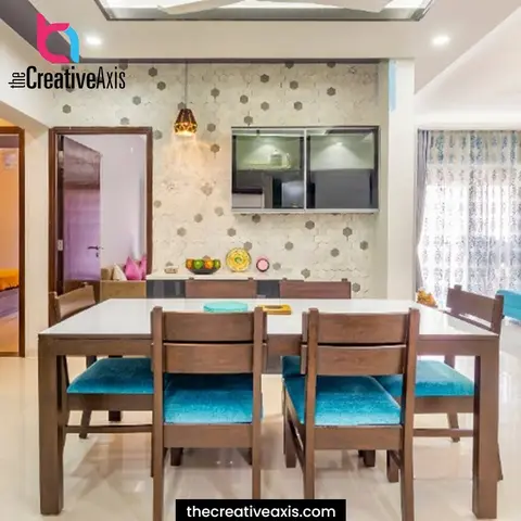Wooden dining table with teal-upholstered chairs set against a grey hexagon mosaic feature wall, a mirrored crockery cabinet, and a single pendant light