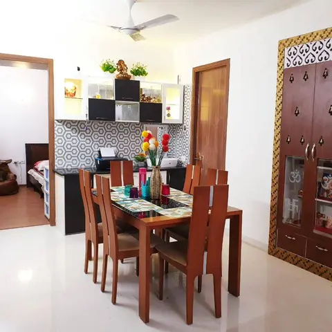 Wooden six-seater dining table beside a hexagon-tile crockery unit and a gold-mosaic framed pooja cabinet with Om-motif glass doors
