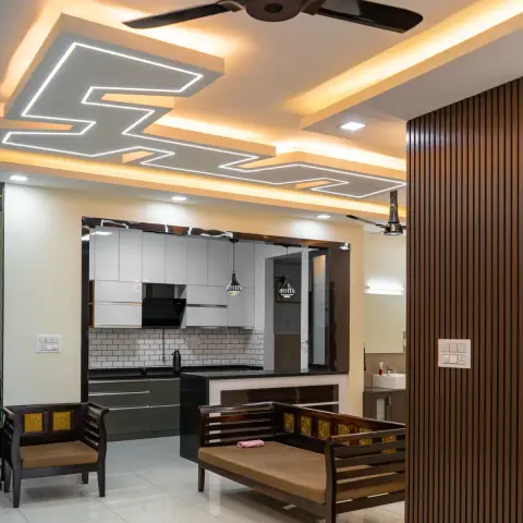 Zig-zag LED profile lines cut across a POP ceiling above a dark teak sofa set with brass-inlay panels